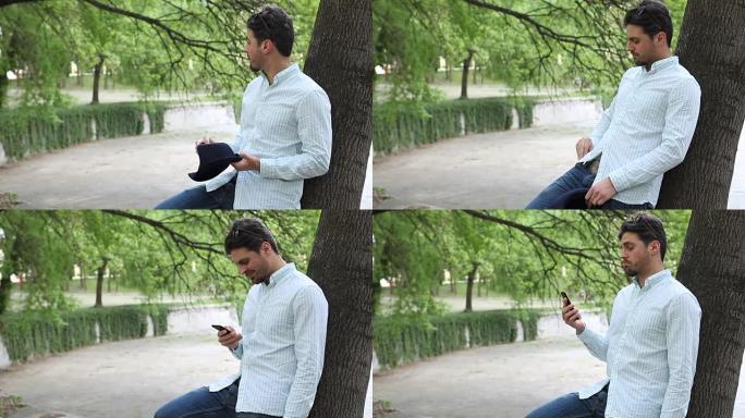 男人在公园里等着，看着他的手机