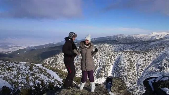 年轻夫妇在山顶上玩得开心，令人惊叹的冬季环境