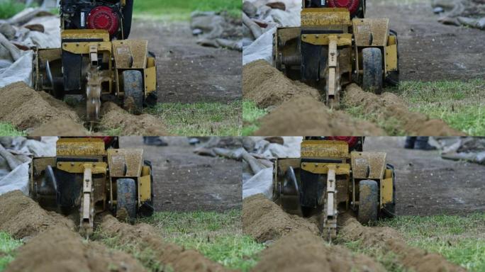 挖沟机打开并在户外将一条沟渠切成草地