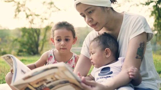 妈妈在户外给小女孩和她的儿子读书