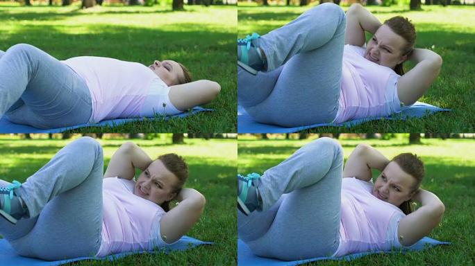 胖女孩几乎不做俯卧撑，躺在公园的垫子上，筋疲力尽的锻炼，节食