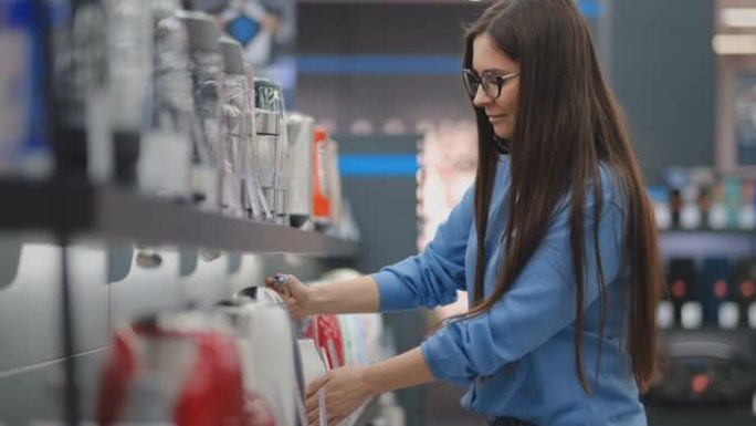电子商店柜台。年轻漂亮的黑发女人手里拿着电水壶，研究模型的价格标签，特征和设计