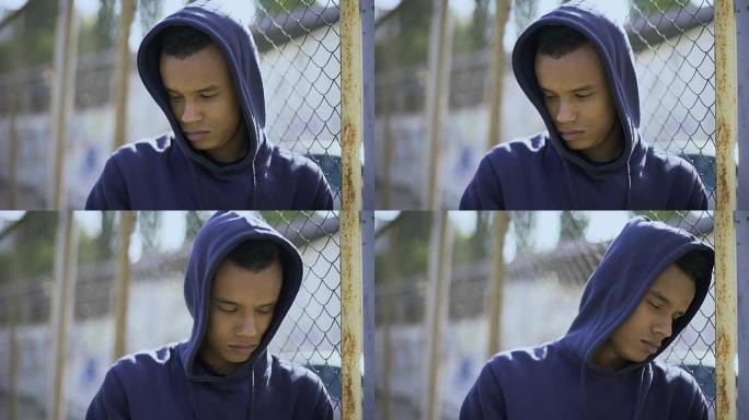 沮丧的男孩靠在篱笆上，移民儿童与家人分离并被拘留