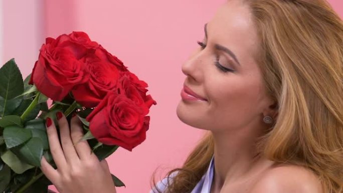 美丽的女人欣赏一束红玫瑰，情人节惊喜