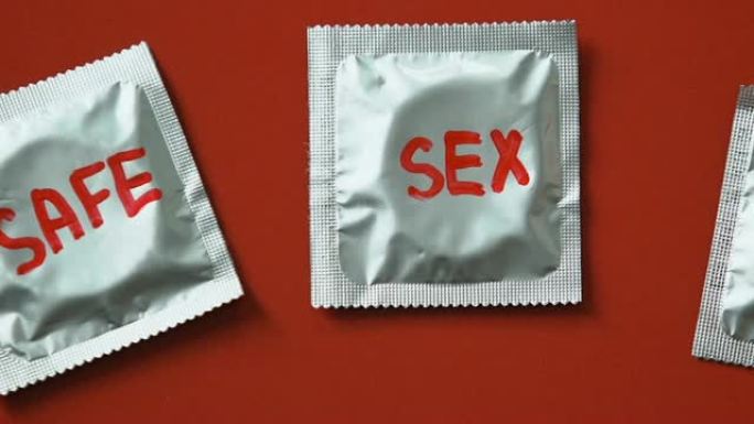 避孕套以红色的性安全字为背景，警惕艾滋病的性病概念