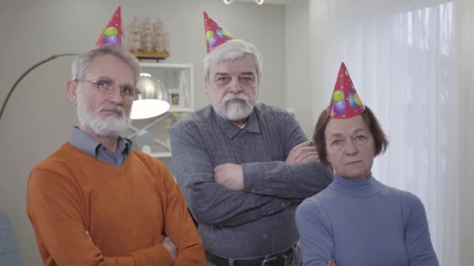 三个戴着派对帽的白人退休人员看着相机的肖像。老人在养老院摆姿势。生活方式，派对，人性。