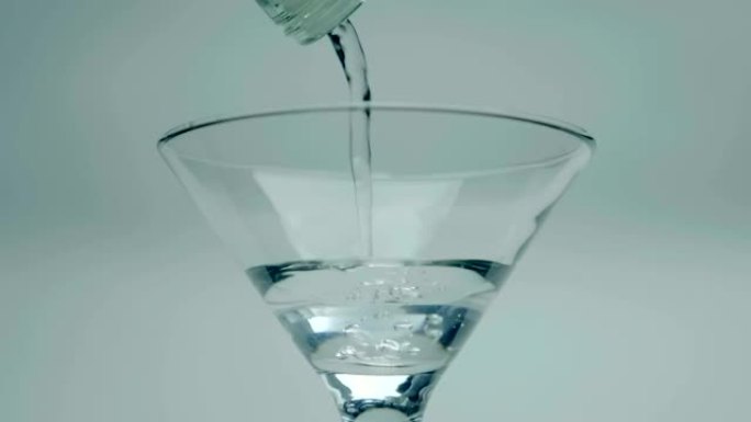 一名男子将马提尼酒 (白葡萄酒) 从瓶子倒入玻璃杯中