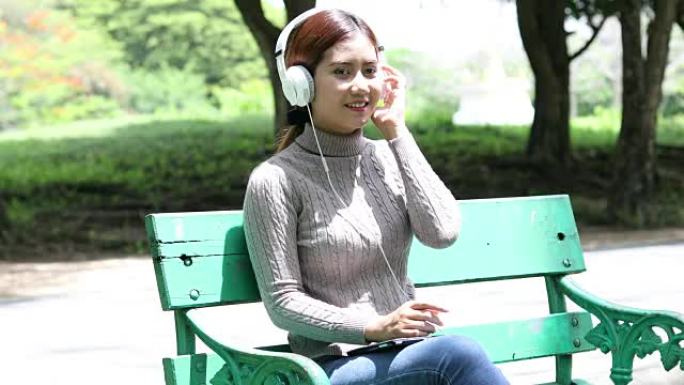亚洲女子放松在公园听音乐