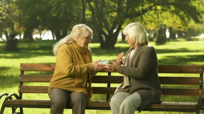 老妇人在公园的长凳上给朋友生日礼物，黄金岁月