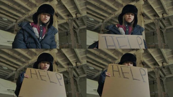 一个穿着脏衣服的无家可归的高加索女孩举起帮助纸板并看着相机的仰视图