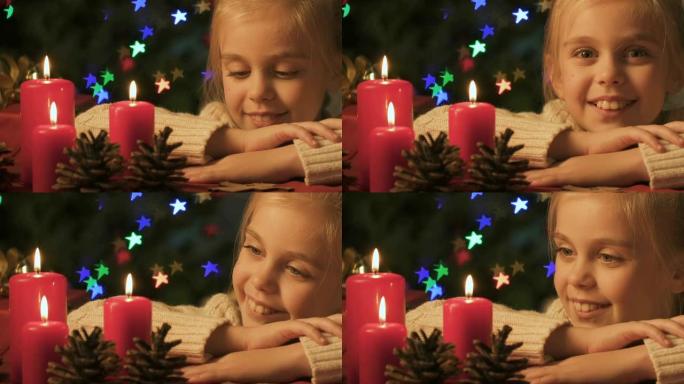 女孩看着燃烧的蜡烛，快乐的童年和对圣诞节奇迹的信念