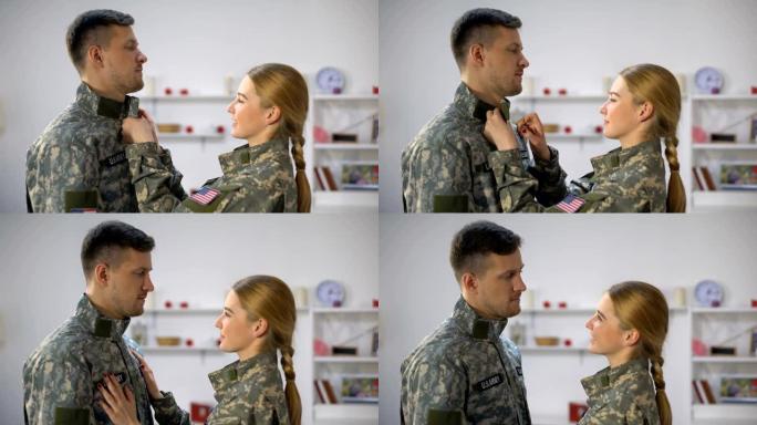 微笑的美国女兵调整制服军人男友，恩爱夫妻
