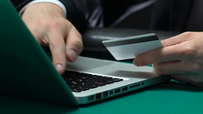 男性手在笔记本电脑上打字男子插入信用卡号，网上银行