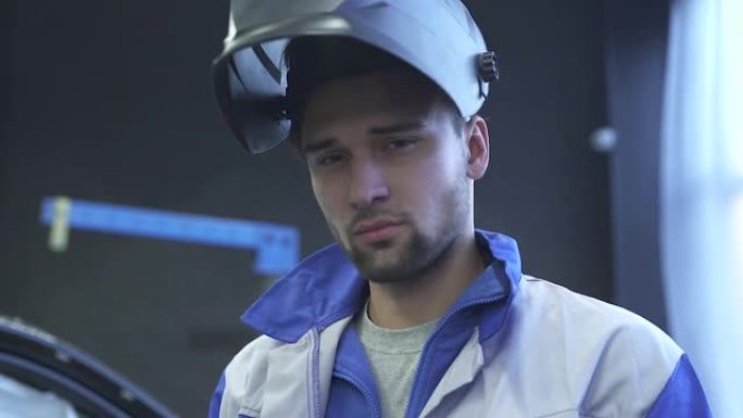 现代汽车服务背景下的焊接头盔年轻专业汽车机械师肖像。慢动作