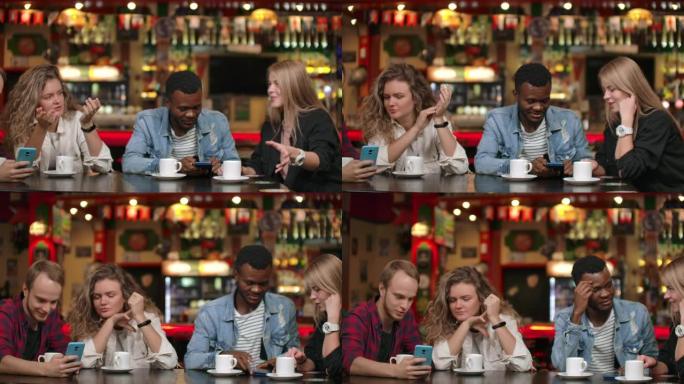 快乐的多元化伴侣与小工具一起玩，一起在智能手机上观看有趣的在线视频，多元文化的年轻朋友笑着看着电话聊