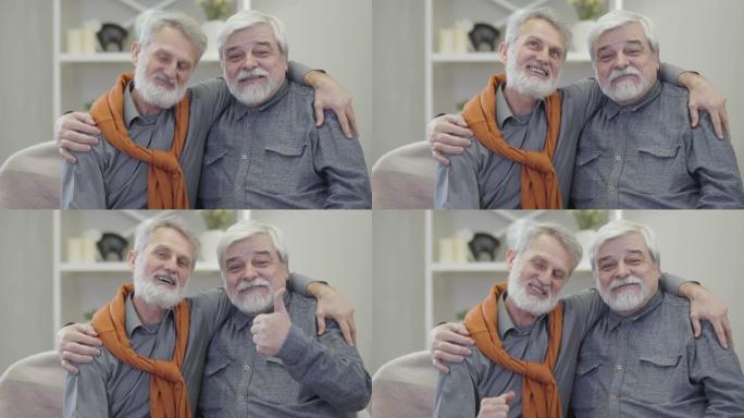 两个白发白人男子的肖像对着镜头说话，竖起大拇指。快乐的老年退休人员在养老院摆姿势。
