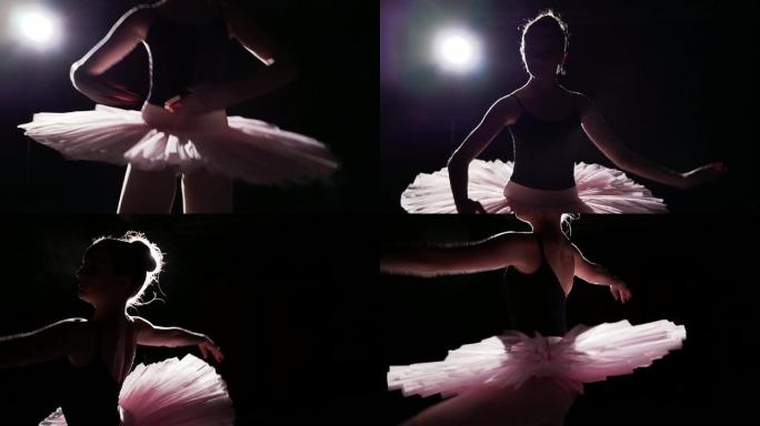 专业芭蕾舞演员在工作室的黑色背景下，在她的脚尖芭蕾舞鞋上跳舞。芭蕾舞演员展示了穿着芭蕾舞短裙和尖头鞋