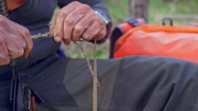 男性荒野生存专家在森林里用干草编织