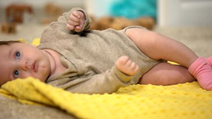 迷人的女婴躺在黄色毯子上，大腿关节发育不良的预防