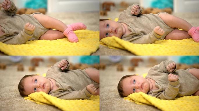 迷人的女婴躺在黄色毯子上，大腿关节发育不良的预防