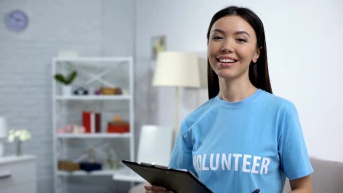 女志愿者做笔记并在镜头前微笑，待办事项清单，慈善项目