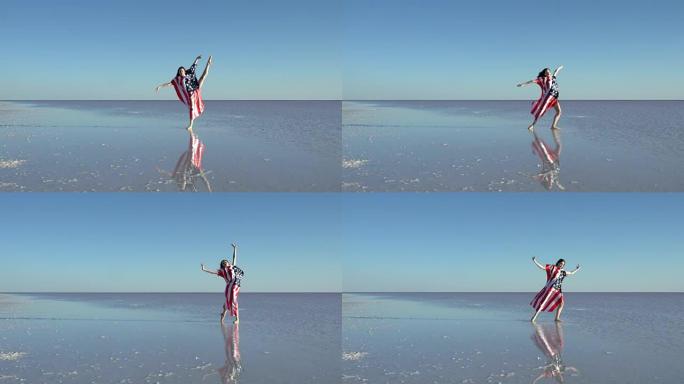 美丽的芭蕾舞演员在水面上举着美国国旗。刮风的一天。