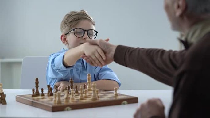 高级男子和小男孩下棋的握手天才孩子尊敬老师