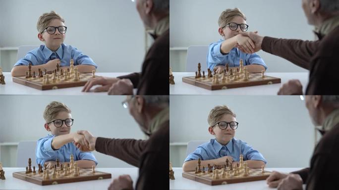 高级男子和小男孩下棋的握手天才孩子尊敬老师