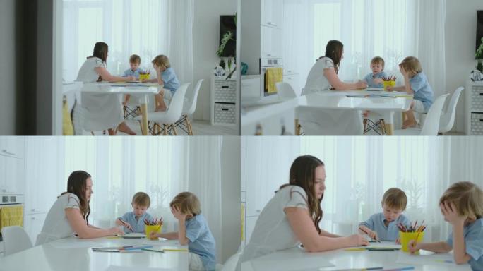 妈妈和她的两个儿子坐在厨房的桌子上，夏天在草坪上画彩色铅笔。男孩学画画，妈妈帮忙画画