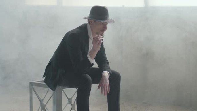 肖像英俊自信的男人戴着一顶帽子，把坐在一个废弃的建筑里的硬币抛起来，接住了。