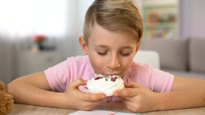 可爱的男孩坐在桌旁吃奶油甜点，糖暴饮暴食，患糖尿病