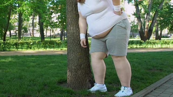 胖子呼吸沉重地站在树旁，做运动以更快地减肥
