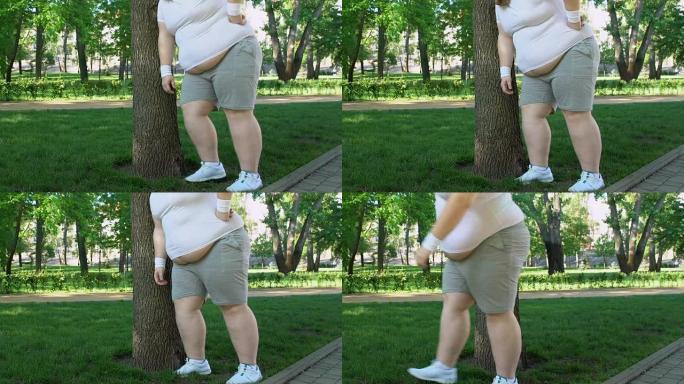 胖子呼吸沉重地站在树旁，做运动以更快地减肥