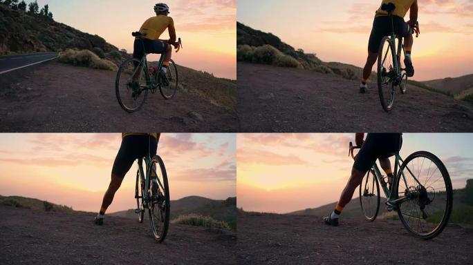 一个穿着骑自行车的人，戴着头盔，坐在公路自行车上，从山顶看日落
