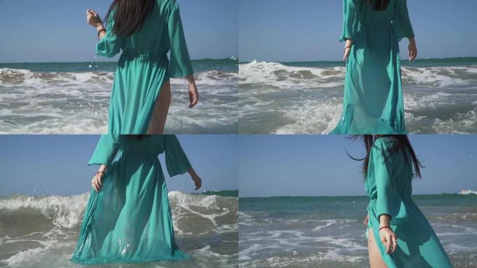 可爱的女人有着完美的身体，穿着绿松石色的裙子，喜欢海浪站在水里。波浪卷过一个穿着浅色夏装的女孩，给了