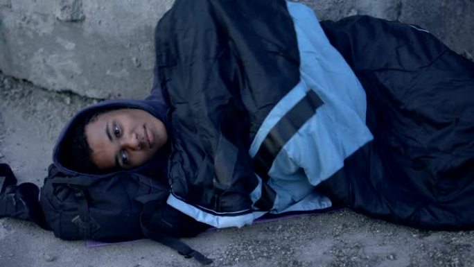 绝望的黑人躺在街上，上面铺着睡袋，贫穷绝望
