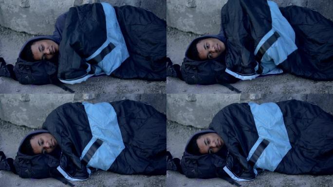 绝望的黑人躺在街上，上面铺着睡袋，贫穷绝望