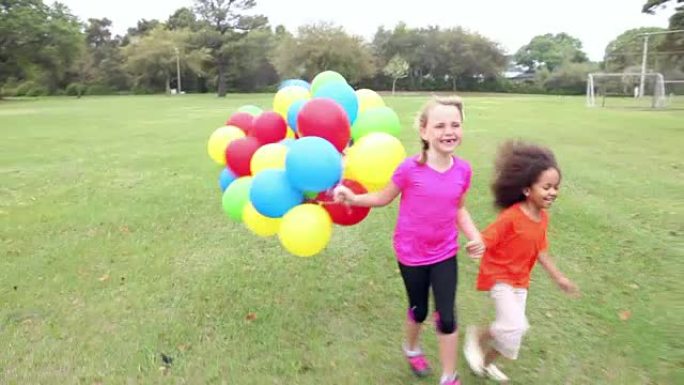 两个女孩牵着手带着一堆气球奔跑