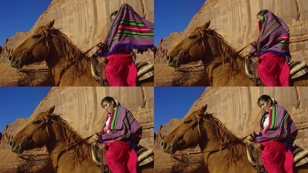在晴朗明亮的日子里，一个十几岁的美国印第安女孩在亚利桑那州/犹他州纪念碑谷沙漠骑马时，在肩膀上披上五