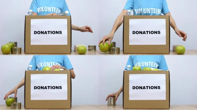 青年志愿者将罐头食品放在工作社会中心的捐款箱桌上