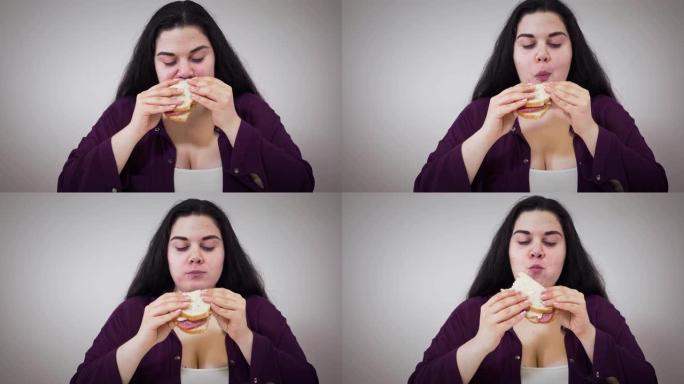 胖胖的高加索女孩嚼三明治的特写。肥胖的年轻女子吃不健康的食物。肥胖，不健康的生活方式，超重问题。