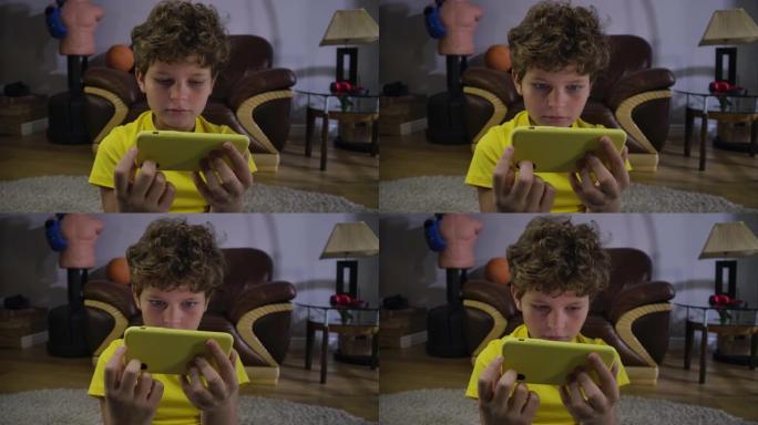 高加索男孩在智能手机屏幕上看电影的恐惧脸。可爱的孩子，灰色的眼睛和卷曲的头发被视频吸收。社交媒体，现
