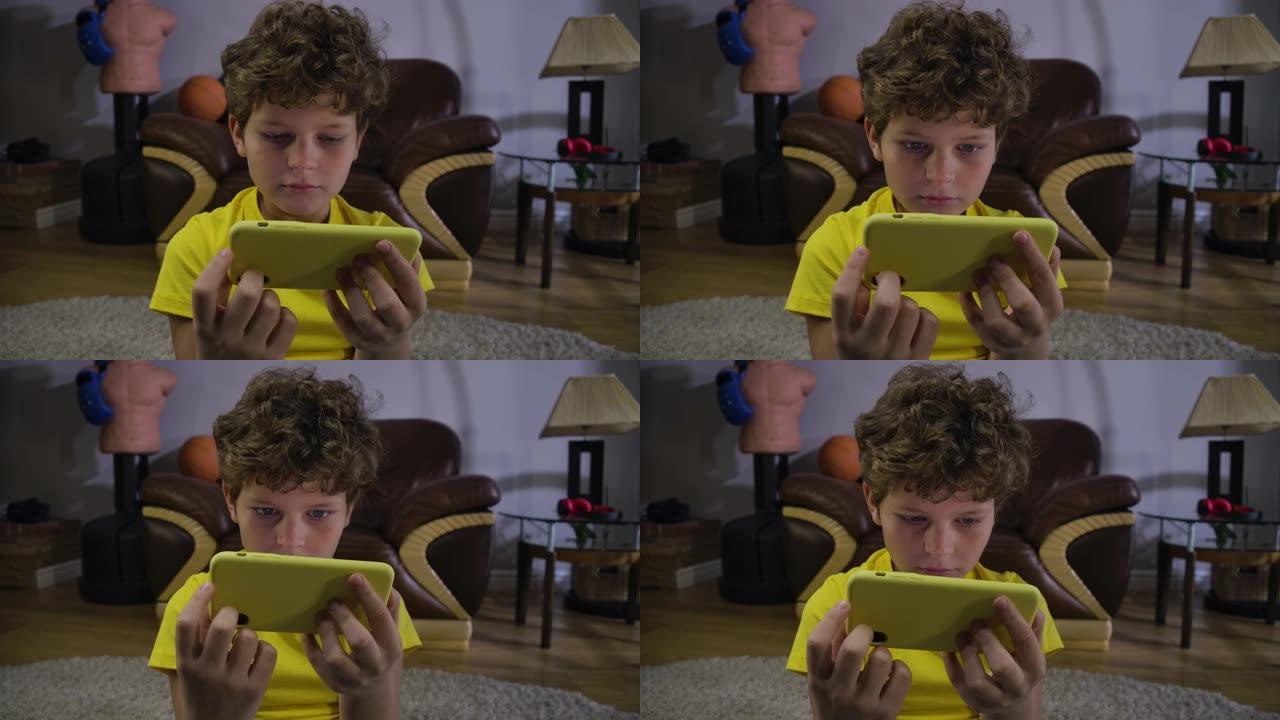 高加索男孩在智能手机屏幕上看电影的恐惧脸。可爱的孩子，灰色的眼睛和卷曲的头发被视频吸收。社交媒体，现