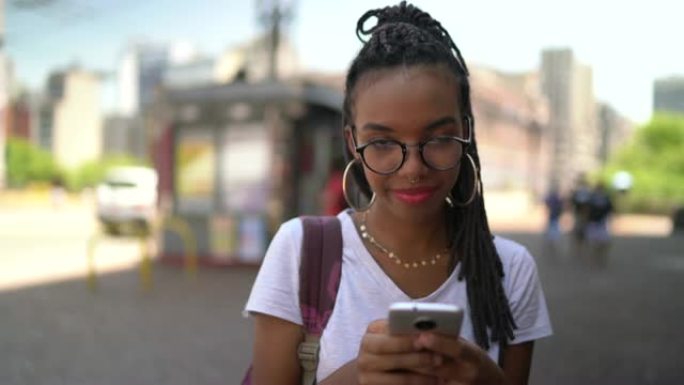 使用智能手机肖像的城市中的非洲拉丁年轻女子