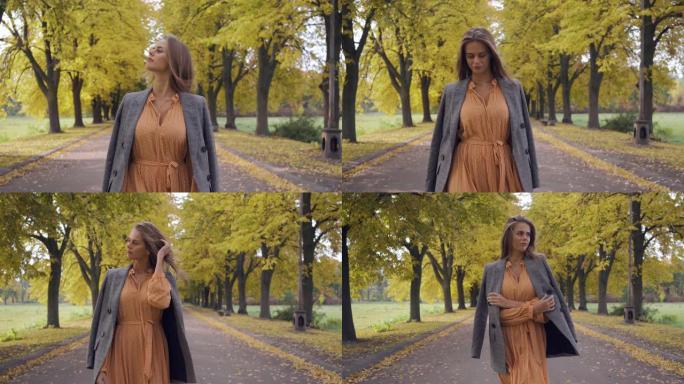 一个穿着芥末连衣裙和方格夹克的微笑黑发女孩在路上行走的肖像。漂亮的高加索女人周末在秋季公园散步。