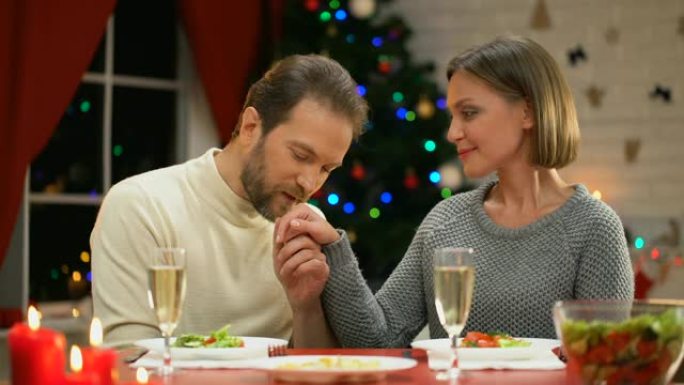 男人小心翼翼地亲吻女人的手，在圣诞节前夕有浪漫的约会，相爱的夫妇