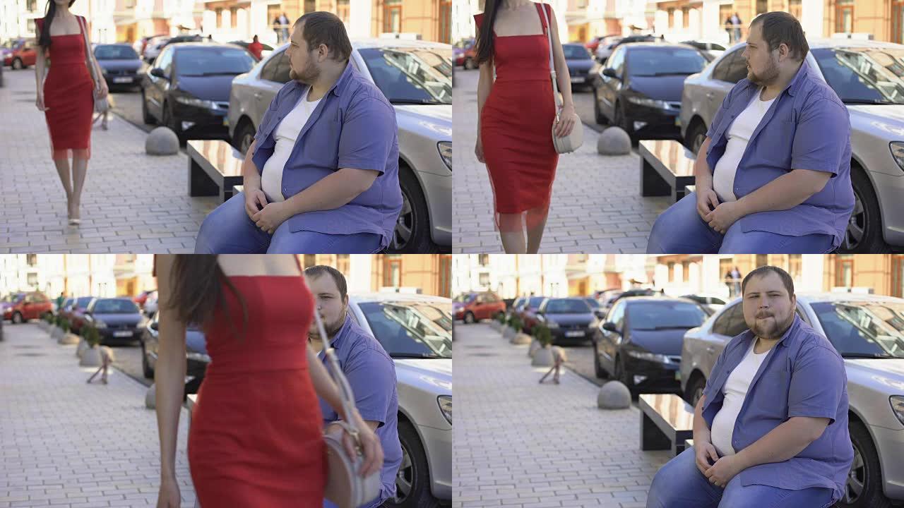 胖单身汉在街上看着穿着红色连衣裙的漂亮女士，舔嘴唇