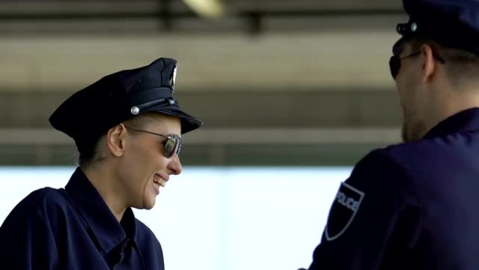 男女警察伙伴大笑，在城市巡逻中休息，休息