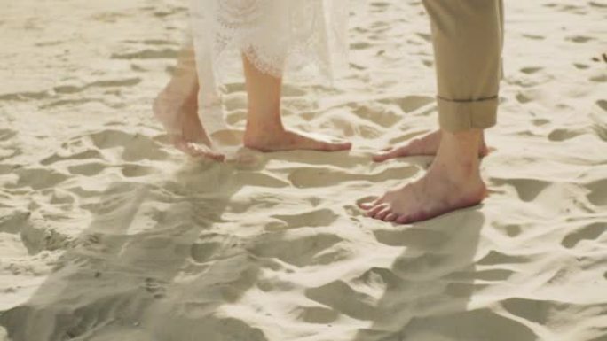 夫妇站在海滩上。靠近脚和波浪。慢动作。