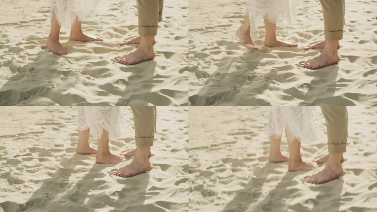 夫妇站在海滩上。靠近脚和波浪。慢动作。